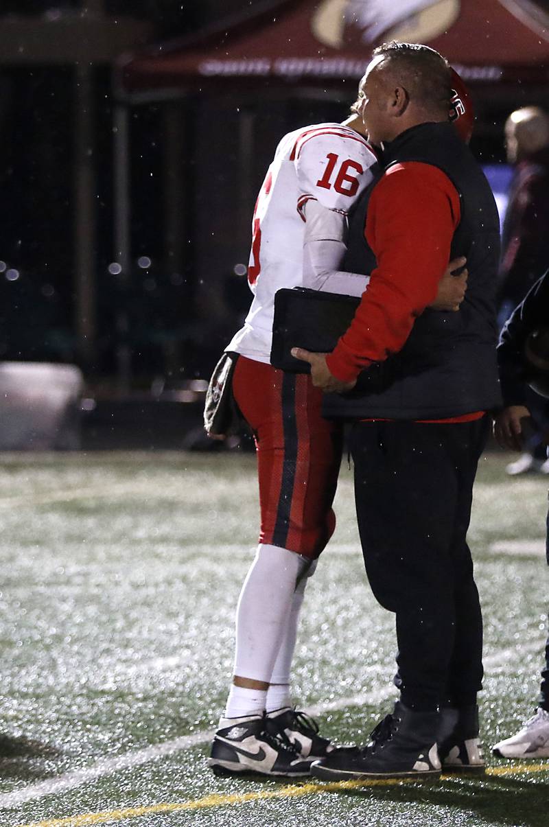 Huntley's Braylon Bower is hugged by assistant coach Craig Kastning after Huntley was defeated by St. Ignatius in a IHSA Class 8A second round playoff football game on Friday, Nov. 3, 2023, at St. Ignatius College Prep in Chicago.