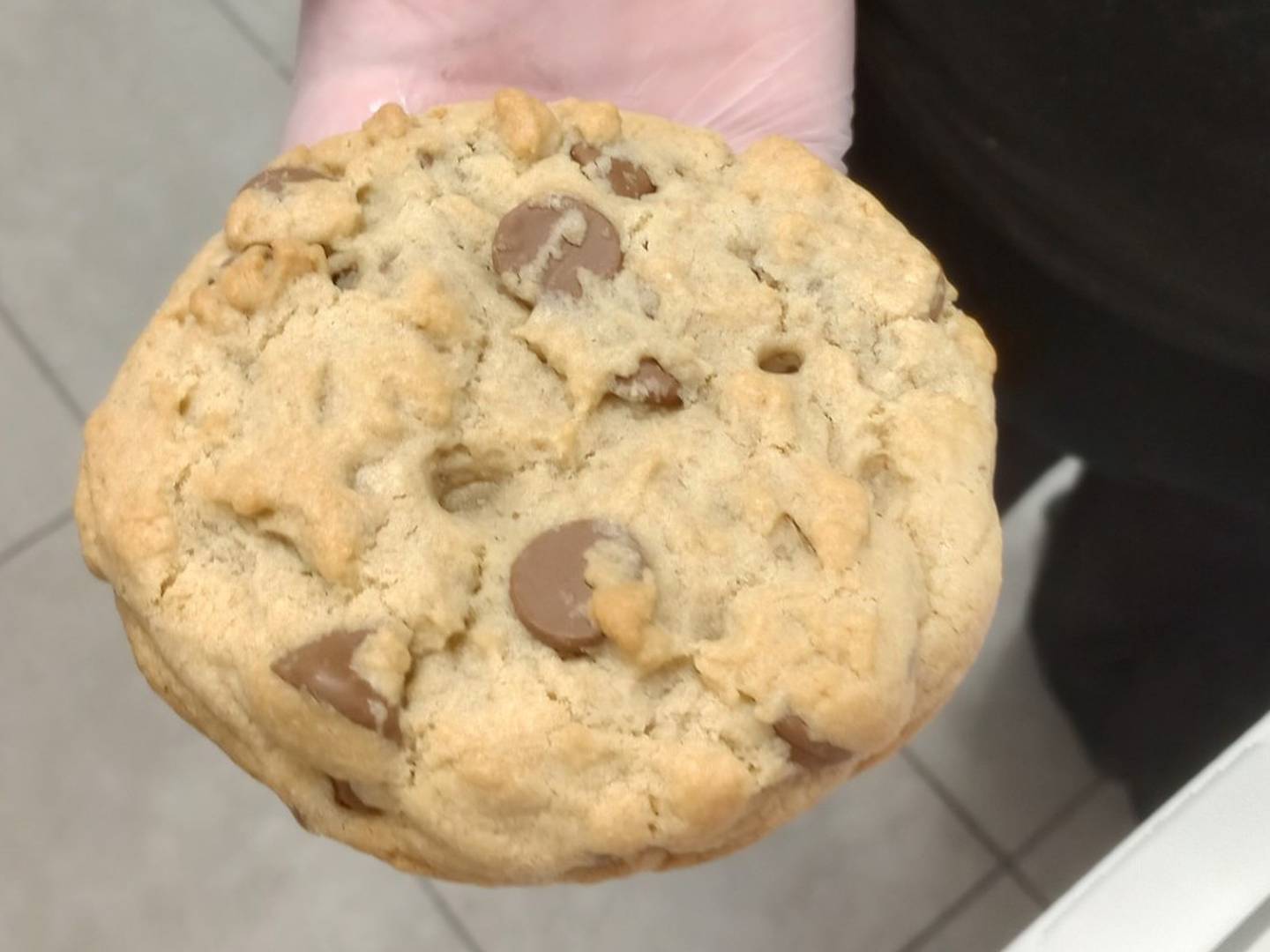 Crumbl Cookies General Manager at the Geneva store, Ashley Strom, shows the size of a regular Crumbl Cookie for which the chain is famous.