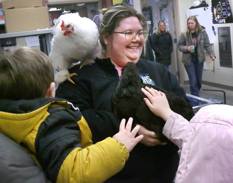 Danya Anderson, a DeKalb High School teacher in the Future Farmers of America program, holds chickens for visitors to pet Wednesday, Feb. 19, 2025, during the DeKalb High School FFA Barnyard Zoo Family Night at the school.