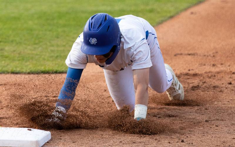 Newman Central Catholic shortstop Garret Matznick slides into first during a pickoff attempt at a game against Hope Academy at Northwestern Medicine Field in Geneva on Monday, June 2, 2025.