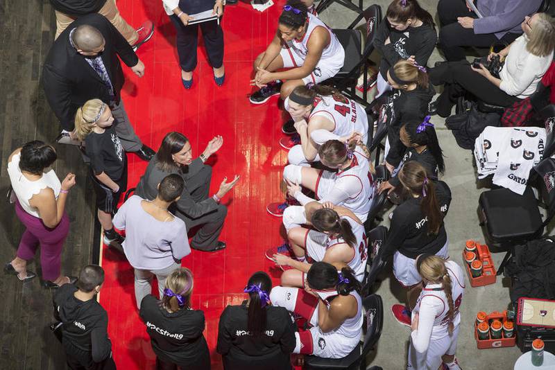 NIU Photo Services – The Northern Illinois women's basketball team huddles together during a timeout. The players and coaches are wearing purple in honor of freshman guard Paulina Castro, who was recently diagnosed with Hodgkin's lymphoma.