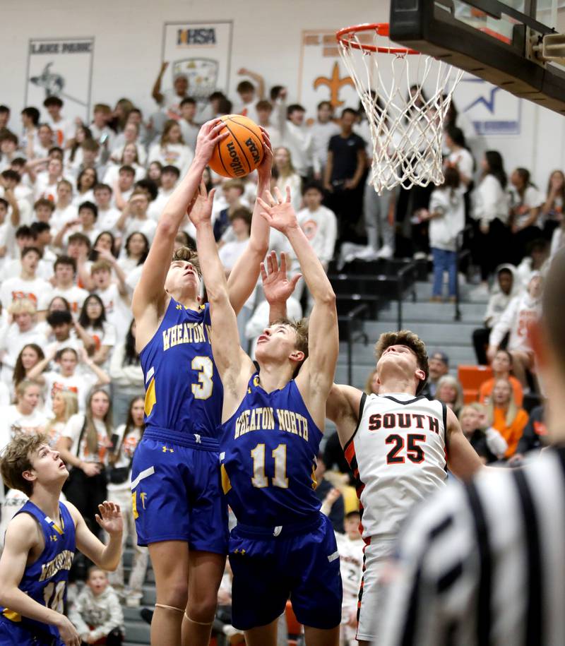 Wheaton North’s Cal MacKay (left) and Matthew Beamer and Wheaton Warrenville South's Brady Goken go after a rebound during a game on Friday, Feb. 7, 2025 in Wheaton.