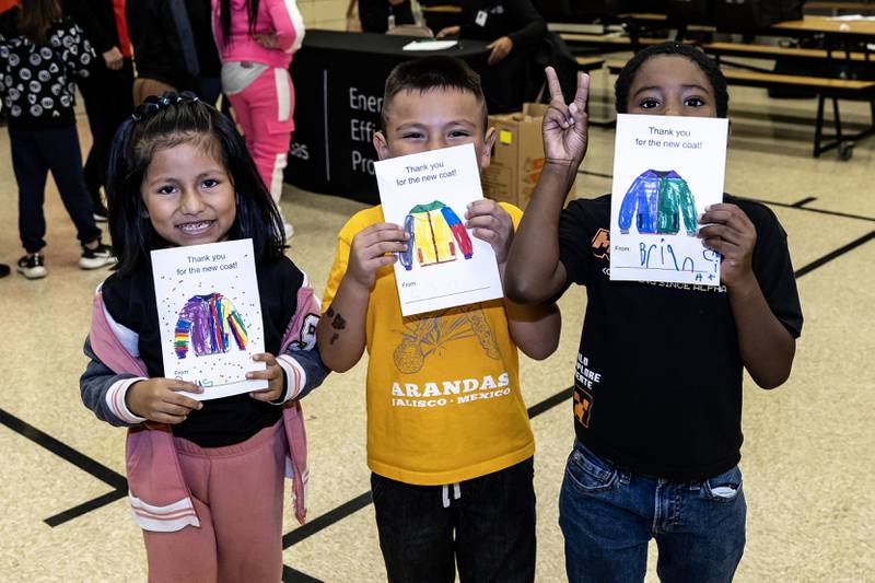 Kindergarteners hold-up thank you cards they designed in gratitude for Nicor Gas, in collaboration with Operation Warm, distributing new winter coats at T. E. Culbertson Elementary School on Nov. 7, 2025.
