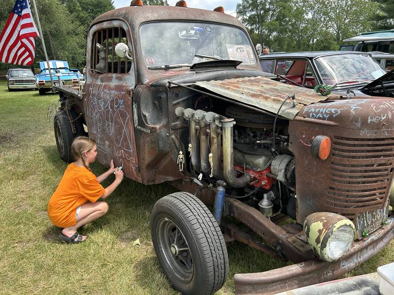 Sadie Williams, 10, of Byron, draws a heart on Ron Renwick's 1956 Ford Rat Road at the Oregon Lions Club's Father Day's Car Show on Sunday, June 16, 2024. Renwick supplied chalk for the kids to draw anything on the truck.