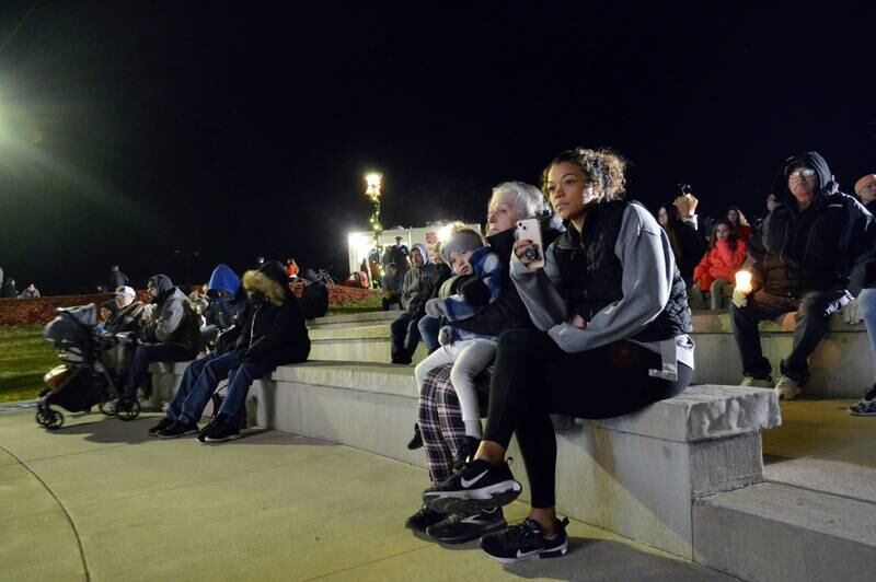 People listen and film on their phones as the names of more than 800 loved ones are read off during Rock Falls' Love Light Tree ceremony at RW&B Park on Friday, Nov. 17, 2023.