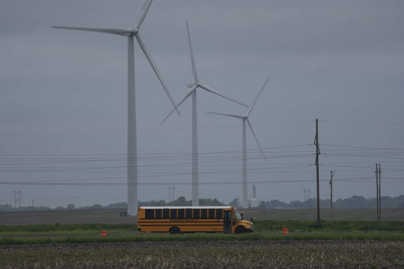 A school bus drives down a road near a field of wind turbines, Thursday, May 9, 2024, in Paxton, Ill. (AP Photo/Joshua A. Bickel)