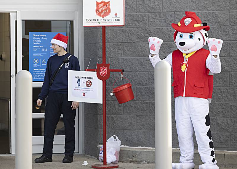 Sterling firefighter Kyle Bell and the Sterling fire mascot greet shoppers Friday, Dec. 15, 2023 at the Sterling Walmart. The fire and police departments both manned the Salvation Army buckets on Friday for a friendly competition on who could collect the most money. Winner gets the hold the City Trophy and have bragging rights the next year.