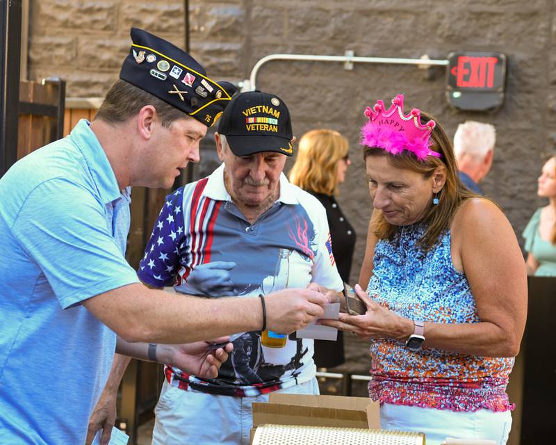 Anna Hurt talks with Joe Morgan of the St. Charles American Legion post and Bryan Fuller of the Geneva post as she buys a ticket for Geneva's 50/50 raffle on Thursday Aug. 21, 2025.