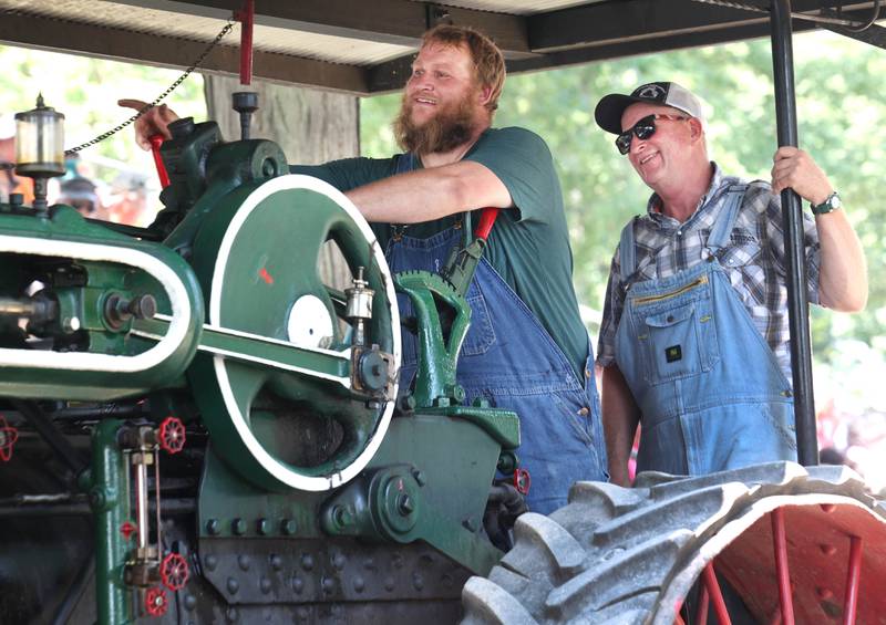 Austin Druien (left) and his dad John, from Holcomb, honk their whistle as they drive their 1914 Case 50 horse power steam tractor in the parade Thursday, Aug. 8, 2024, during the 67th annual Sycamore Steam Show and Threshing Bee at Taylor Marshall Farm.