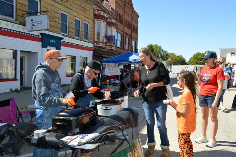 Rachel Castaneda, of Oregon, (center right) and Evelyn Castaneda, 9, watch and wait as Kirby Witmer (center left) prepares cups of Southwest chili for the them.
