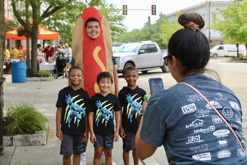 Crislon Garcia takes a picture of hot dog mascot Chalo Herrera standing with, from left, Larry Crain, Leo Dallgas-Frey, and LaVelle Crain during Hot Dog Day on Friday in downtown Sterling.