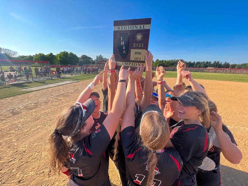 Yorkville softball players raise the 4A regional championship plaque after defeating Plainfield North for the class 4A regional championship at Yorkville High School on Friday, May 26, 2023.