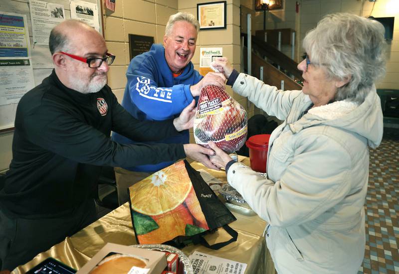 Cheryl Johnson, from Cortland, hands her turkey donation to Shadow Gentry, (left) of DeKalb, and TD Ryan, host of the TD Ryan Unleashed podcast, during Ryan’s Let’s Talk Turkey Thanksgiving food drive Friday, Nov. 21, 2025, at the Salvation Army food pantry in DeKalb.