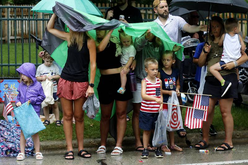 People try to keep dry on Sunday, July 7, 2024, during Crystal Lake’s annual Independence Day Parade on Dole Avenue in Crystal Lake. This year’s parade feature close to 100 units.