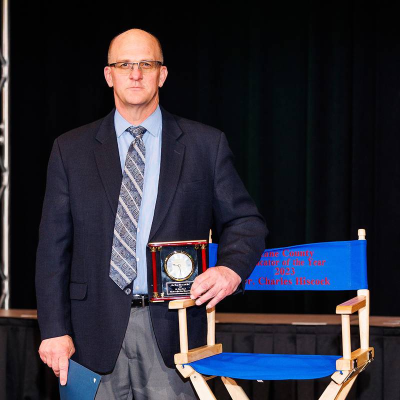 Dr. Charles Hiscock, 2023 Kane County Educator of the Year, next to his personalized chair given by the Kane County ROE in recognition of his achievements.