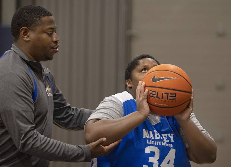 Coach Eli Townsend positions Amea for the shot Wednesday, Dec. 18, 2024, during Special Olympic basketball practice. The team took second last year and are excited try and compete for the gold medal this year.