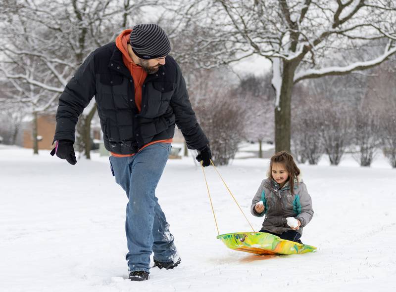 Christian Wimber, left, pulls his daughter Margot Wimber, 6, on a sled in Prairie Lathem Park in Batavia on Saturday, Jan. 6, 2023. The Kane County Area received about one to two inches of snowfall late Friday night into Saturday morning.