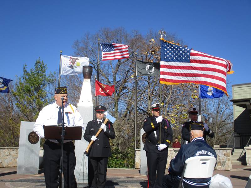 Oswego American Legion Post 675 Commander Kris Kearns delivers an address for the Veterans Day ceremony on Nov. 11, 2022 in downtown Oswego. He is backed by an honor guard from the Oswego Fire Protection District.