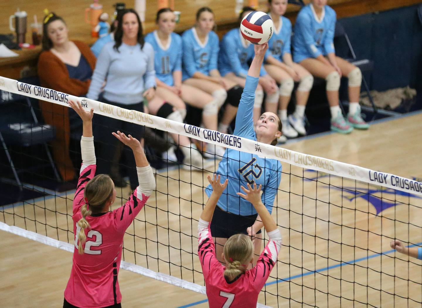 Marquette's Kinley Rick spikes the ball past Serena's Anna Hjerpe and teammate Emily Hoffman in a match this past season in Bader Gymnasium at Marquette High School.