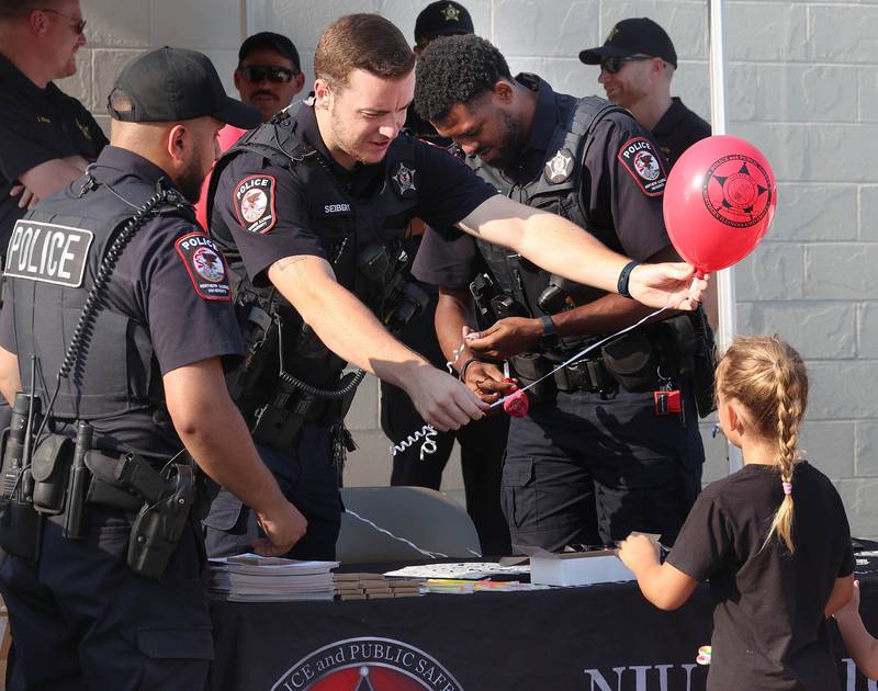 Northern Illinois University Police officers hand out balloons Tuesday, Aug. 5, 2025, at their booth during National Night Out in the Hy-Vee parking lot in Sycamore.