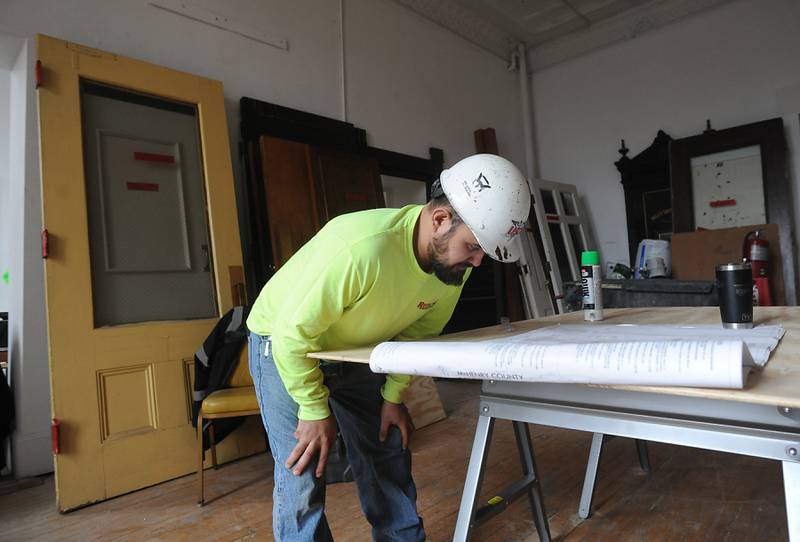 Jonathan Alvarez of USD, a demolition company, reads the demolition plan in the Old Courthouse and Sheriff’s House in Woodstock on Tuesday, March 1, 2022, as the renovation of the building continues.