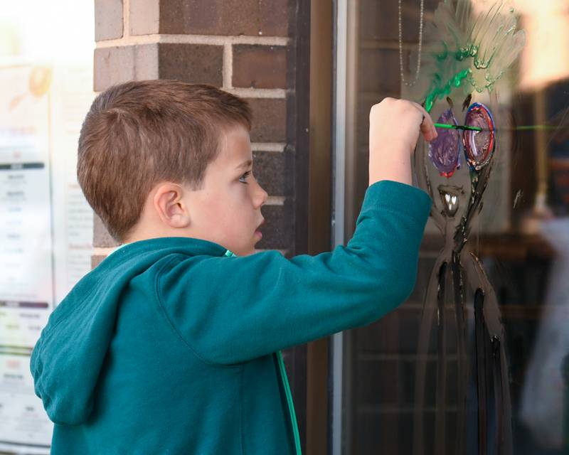 William Bailey, 8, of Downers paints a window on Saturday Oct. 26, 2024, in downtown Downers Grove during a Halloween event.