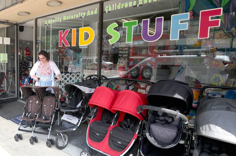 Vickie Obermiller, owner of Kid Stuff at 149 East Lincoln Highway in DeKalb sets some merchandise on the sidewalk Tuesday, May 24, 2022. Road construction will be starting soon on the section of Lincoln Highway between First and Fourth Streets which will afford some businesses more sidewalk space in front of their stores.