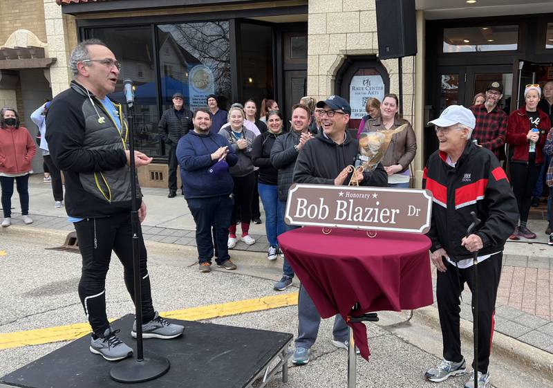 Crystal Lake Mayor Haig Haleblian, left, speaks during an unveiling Sunday, May 1, 2022, of a new "Bob Blazier Dr" sign that will go up in honor of Bob Blazier, right, on South Williams Street downtown.