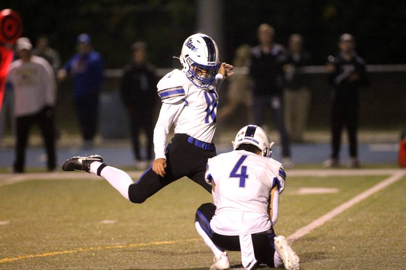 St. Charles North’s Hunter Liszka kicks the extra point with teammate Aidan Leal holding the ball during a game at Wheaton North on Friday, Sept. 8, 2023.