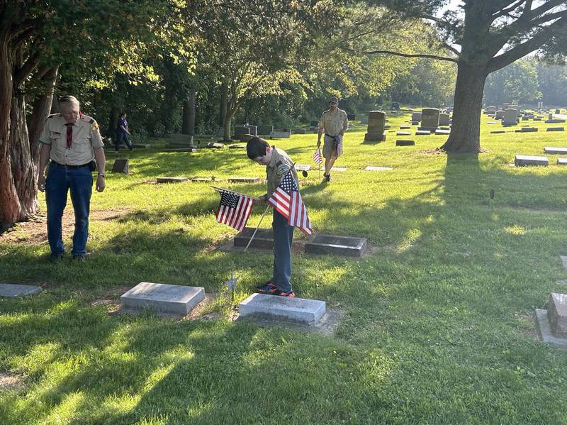 Isaac Blevins, 12, of Morrison, places a flag at a veteran's gravesite Saturday, May 18, 2024, at Grove Hill Cemetery in Morrison.