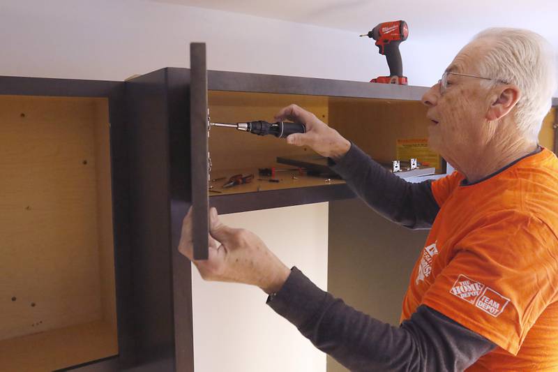 Tom Powers, from Home Depot, installs new cabinets in veteran Craig Taylor's home on Thursday Jan. 16, 2025. The kitchen remodel for Taylor is part of the 30 Days for 30 Vets program.