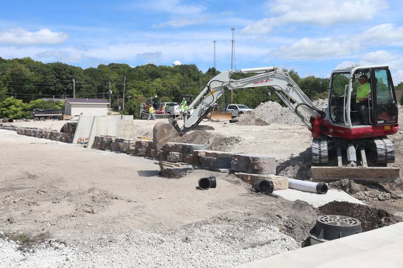 An excavator moves dirt near a partially built wall at the "Market on Mill" retail plaze on Tuesday, Aug. 13, 2024 downtown Utica.