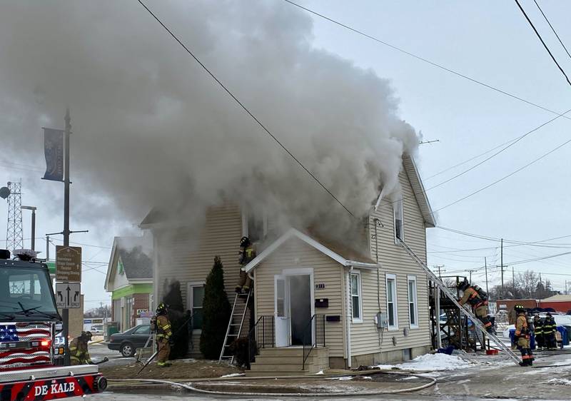 A firefighter on a ladder works to break the upstairs window to a two-story duplex to get water into the structure on Saturday, Jan. 24, 2026, at Seventh Street and East Lincoln Highway in downtown DeKalb. Fire Chief Luke Howieson said the rampant flames spread too quickly into the walls for it to be safe for firefighters to remain in the building.
