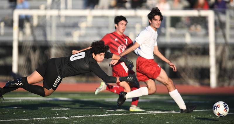 Hinsdale Central goalkeeper Martin Contreras dives as a shot by Naperville Central’s Joey Loduca, background, gets past him for a goal in the Class 3A East Aurora supersectional boys soccer game on Tuesday, November 1, 2022.