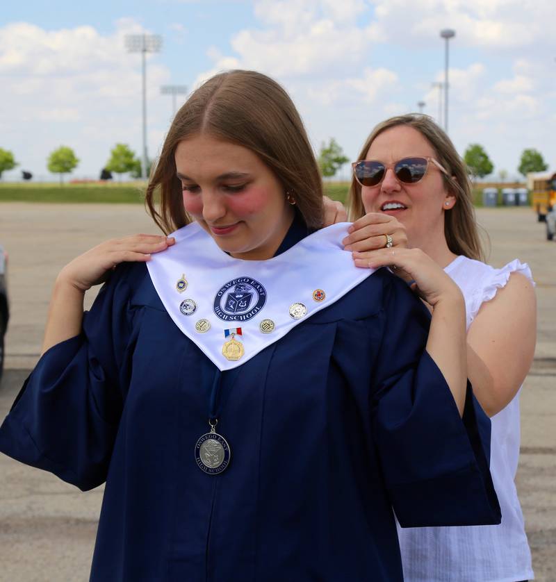 Jessica Salins gets help putting on her graduation stole from her mom Jennifer before the Oswego High School Class of 2024 Commencement Ceremony on Saturday, May 18, 2024 in DeKalb.