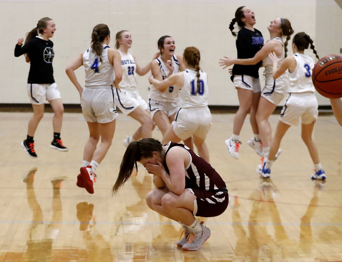 Marengo’s Addie Johnson reacts to the loss as Rosary players celebrate their one-point overtime win over Marengo during a IHSA Class 2A Regional semifinal basketball game Monday evening, Feb. 14, 2022, between Marengo and Rosary at Marian Central High School.