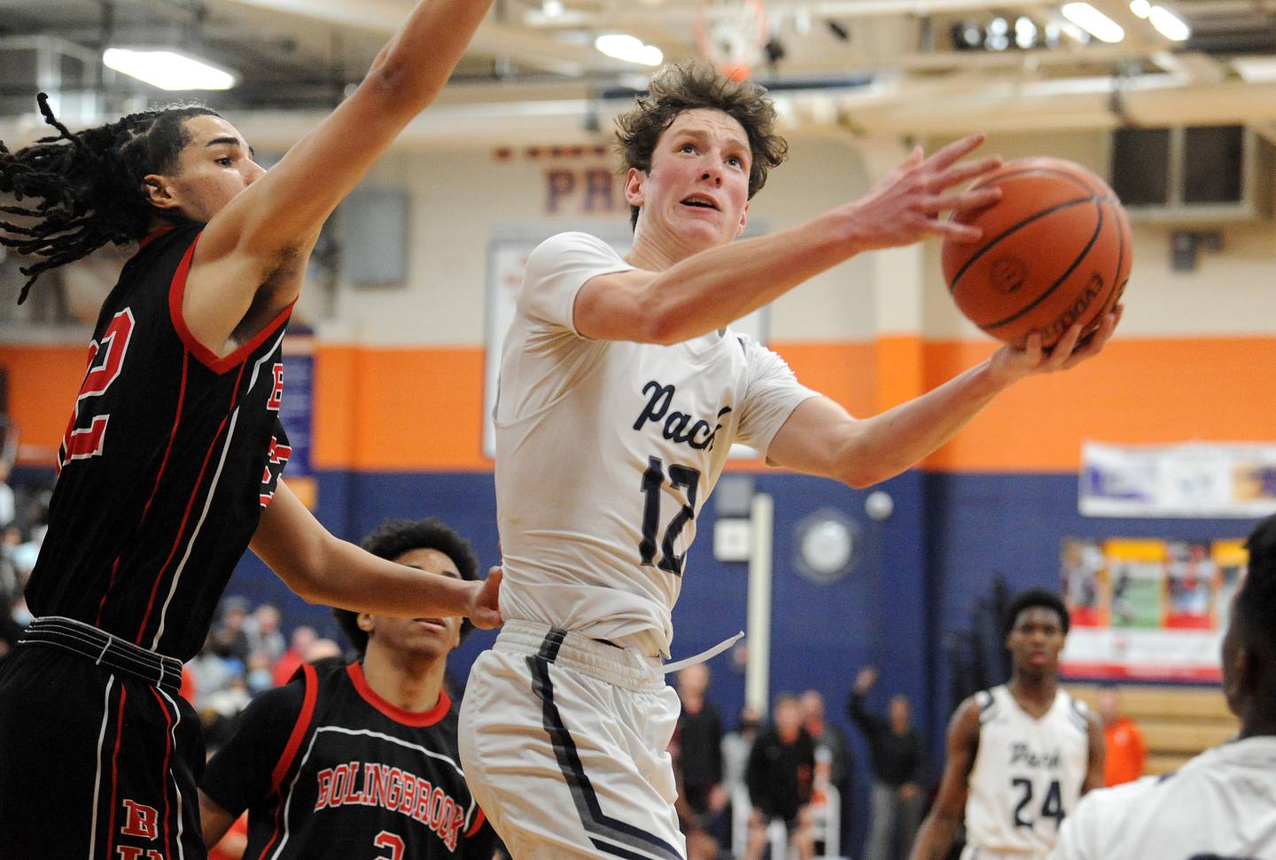 Oswego East's Ryan Johnson (12) glides past Bolingbrook's Donaven Younger during a Class 4A sectional final on Friday, March 4, 2022 at Oswego High School.