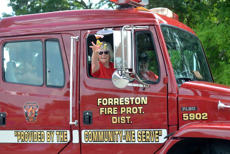 Jean Burton, a Forreston Fire Trustee, tosses candy to the crowd from a Forreston fire truck that her husband, Jeff, was driving during the Let Freedom Ring parade on Tuesday, Juky 4. The parade was held under sunny skies with temperatures nearing 90 degrees during the Mt. Morris festival.