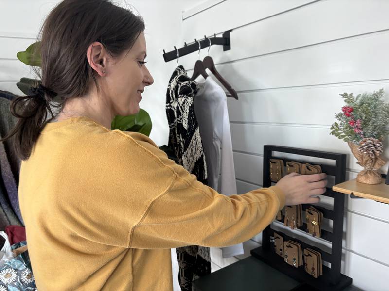 Denae Hintze organizes earrings at her Huntley store, Wild in Ink. Oct. 28, 2025.