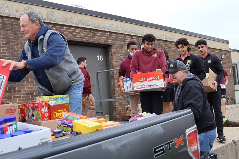 Montini Catholic juniors Isaiah Mason, Santino Florio and Vince Irion help members of Christ the King Church load up their truck with food donations.