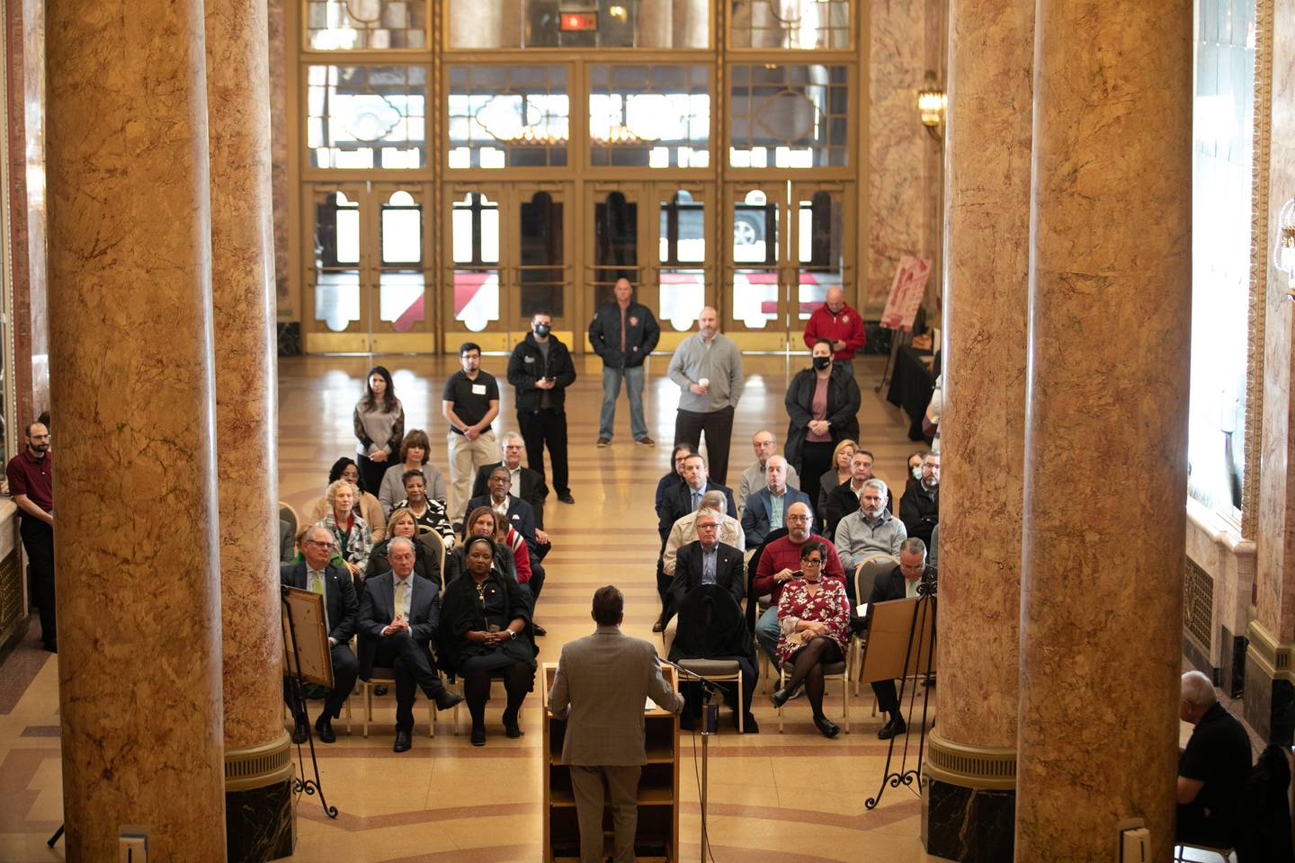 People listen as State Rep. Larry Walsh Jr. speaks at a press conference to announce the Rialto Square Theater will be getting a five-million dollar grant, March 18, 2022