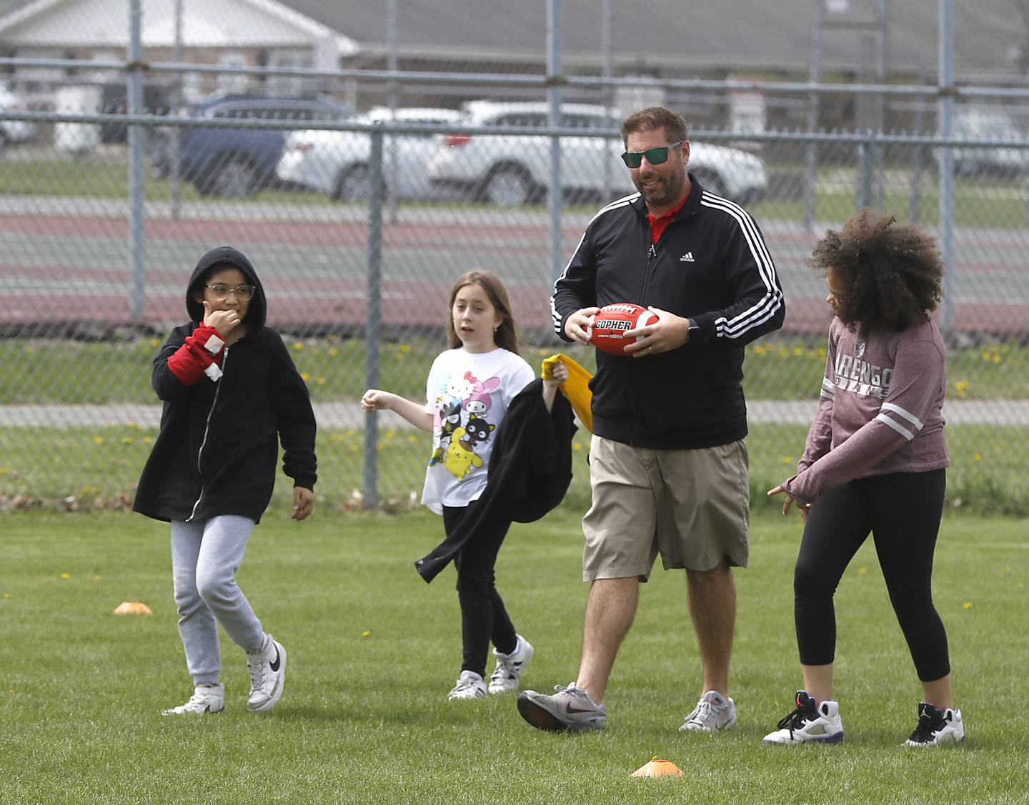 Jeremy Burke, a physical education teacher at Marengo Community Middle School, walks with kids as they play capture the flag on Friday, April 28, 2023.