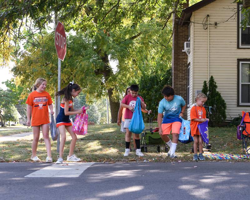 Young Oswego community members pick up candy during the Oswego High School homecoming parade on Sunday Sept. 15, 2024, that traveled through downtown Oswego.