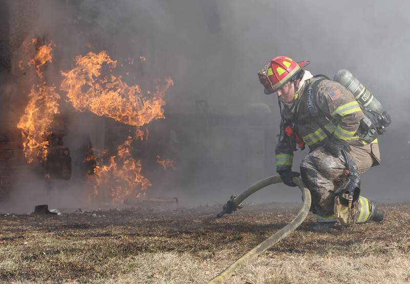 La Salle firefighter Mitch Walter, lifts up a hose in the frigid cold to fight a fully engulfed house fire in the 800 block of Bucklin Street on Friday, Jan. 23, 2026 in La Salle.