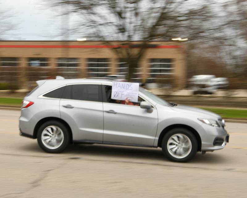 Vehicles drive by with signs during the Hands Off Demonstration held on Saturday April 5, 2025, held on Ogden Ave. in Lisle near the Tesla dealership.