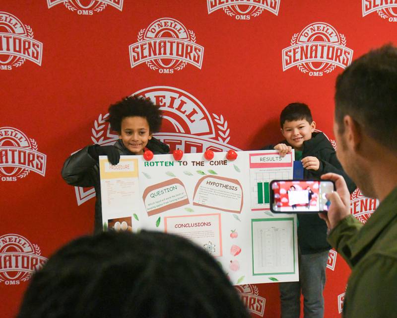 Students Sebastien Robinson, left, and Reece Framarin pose on Saturday Jan. 25, 2025, with their first prize ribbons and science project where they tested different liquids to prevent apples from browning during the Downers Grove District 58 science fair held at O’Neill Middle School.