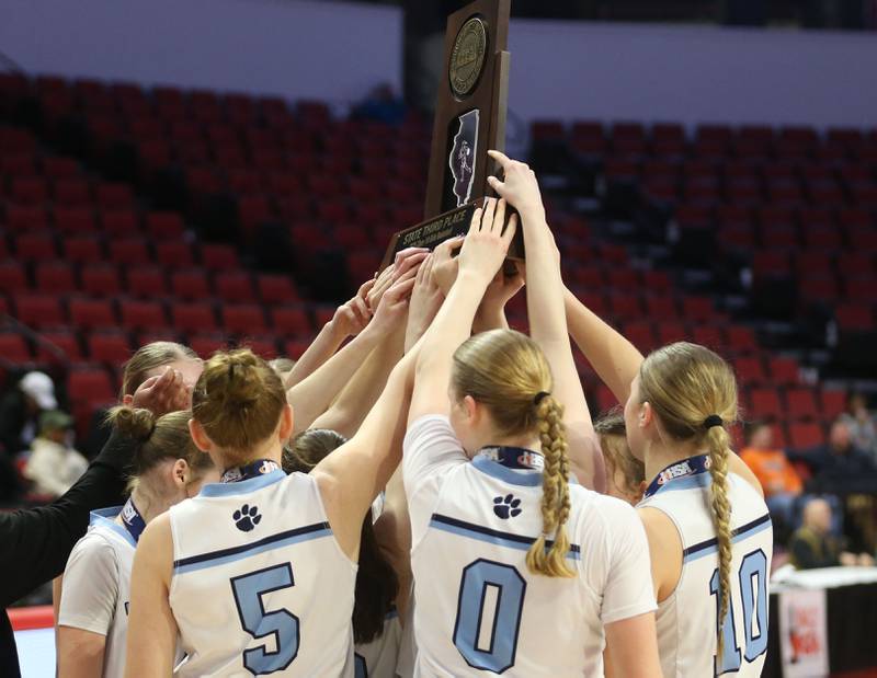 Members of the St. Edward girls basketball team hoist the Class 1A third place trophy on Friday, March 7, 2025 at CEFCU Arena in Normal.
