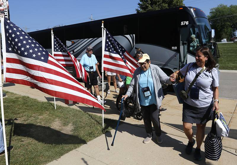 Returning Honor Flight veterans walk a flag-lined sidewalk into the gym at McHenry Community High School’s Upper Campus for a homecoming celebration on Sunday, Aug. 27, 2023.