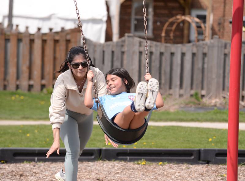 Elizabeth Santana of Stickney pushes Mila Silva of Cicero on the swings at Sedgwick Park Sunday, April 14, 2024.