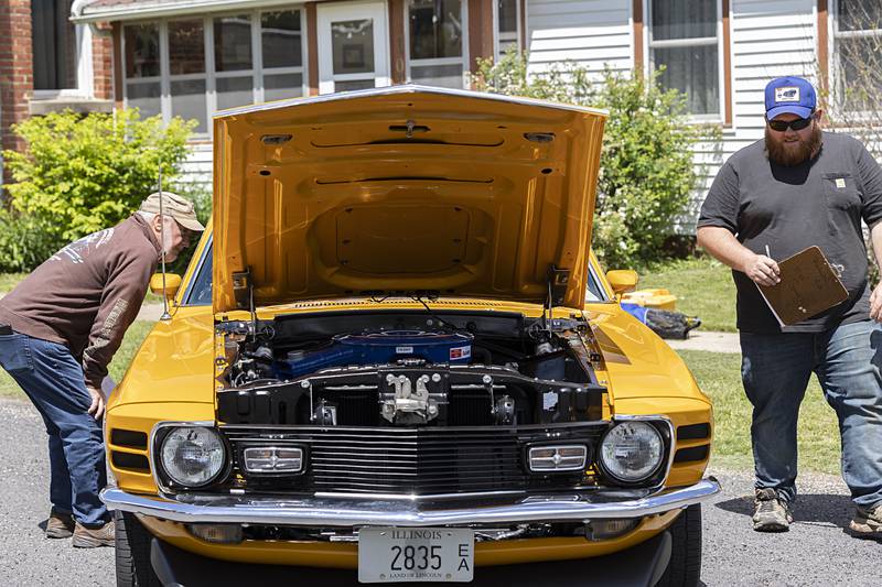 Dave White (left) and Ben McCasky judge Bud and Kim Cruse’s 1970 Ford Mustang Saturday, May 11, 2024 in the Lincoln Highway Car Show in Franklin Grove.